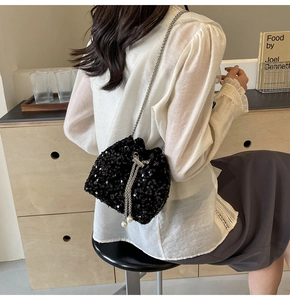 Détail du sac seau noir à paillettes avec chaîne argentée et perle sur un mannequin