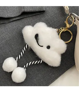 Detail of white plush cloud charm with embroidered face and golden metal keychain