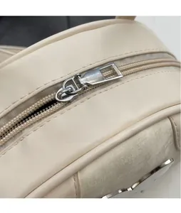 Detailed close-up of the silver metal zipper and smooth beige faux leather of the bag