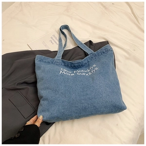 Détail du sac cabas en jean bleu avec broderie blanche 'Less Mondays More Sundays'