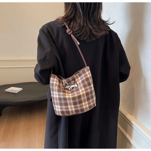 Brown plaid shoulder bag with dachshund embroidery on a model wearing a black coat
