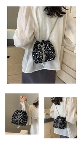 Close-up of black sequined bucket bag with silver chain strap and pearl pendant detail