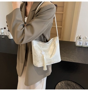 Detail of cream jacquard shoulder bag with bamboo patterns and elegant tassel charm