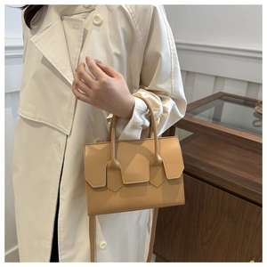 Detail of light brown leather handbag with flap design and detachable shoulder strap