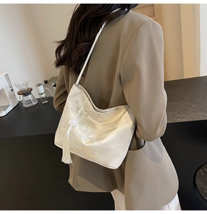 Detail of off-white satin tote bag with traditional bamboo print and elegant tassel charm