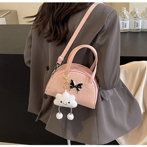 Pink leather saddle bag with butterfly charm and fluffy cloud keychain on a model