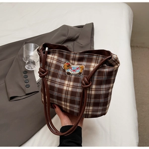 Close-up of brown plaid hobo bag featuring animal embroidery and leather knotted handle