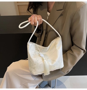 Detail of cream jacquard bucket bag with bamboo patterns and elegant tassel charm