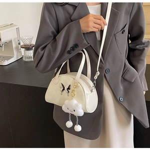 Detail of a chic cream mini square bag with silver butterfly clasp and cloud plush charm