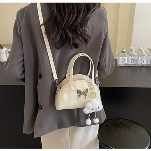 Close-up of cream saddle bowling bag featuring a silver butterfly and cloud charm