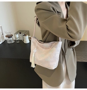 Detail of pink jacquard shoulder bag featuring intricate cloud patterns and white tassels