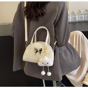 Off-white saddle bag with silver butterfly charm and fluffy cloud pendant in use