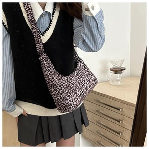 Detailed view of leopard print canvas hobo bag worn crossbody in a lifestyle setting