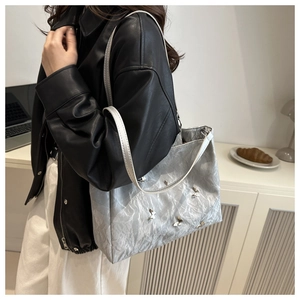 Detailed view of metallic silver tote bag with butterfly charms on model in office setting