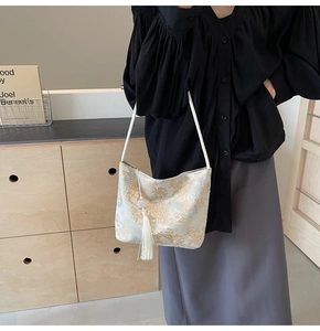 Detail view of a Chinese-style off-white shoulder bag with mountain prints and long tassels