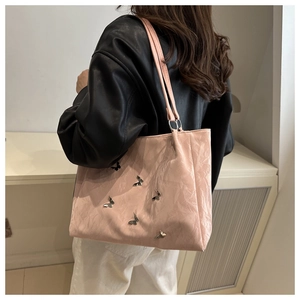 Detail of light pink tote bag with silver metal butterfly accents and satin pleats