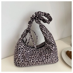 Detail of ruched shoulder strap and leopard print fabric on a crescent handbag