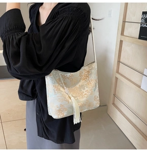 Close-up of beige silk handbag featuring gold Chinese embroidery and white silk tassel