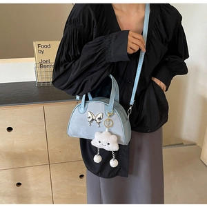 Detail of sky blue suede bowling bag featuring a metal butterfly and plush cloud charm