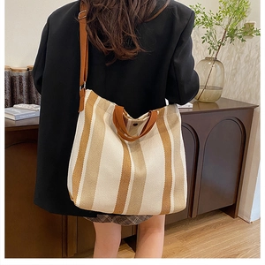 Detail shot of a large striped canvas tote bag showing its size and texture on a model