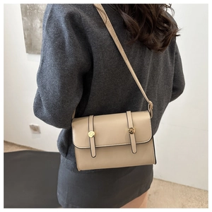 Detail view of cream crossbody bag featuring smooth PU leather and gold rivet accents