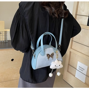 Detail of light blue saddle bag with butterfly clasp and plush cloud pendant on a model