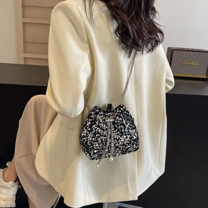 Chic black sequin bucket bag with chain strap and pearl drawstring on a female model