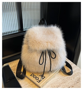 Detail showing the plush faux fur texture and black drawstring closure on the beige backpack