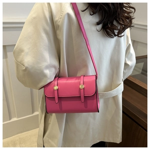 Hot pink small square handbag with golden buttons shown on a shoulder in a stylish interior