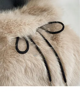 Macro shot of plush cream faux fur texture with black drawstring and silver metal tip
