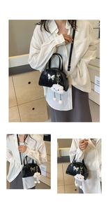 Detail of black crossbody saddle bag with silver butterfly charm and plush cloud pendant