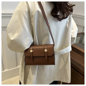 Brown leather crossbody square bag detail on white trench coat with gold magnetic buckle