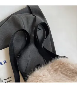 Close-up of beige plush tote bag with smooth black woven straps on a magazine background