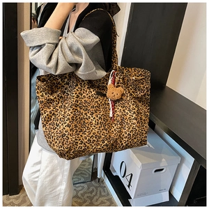 Detail of large capacity leopard print tote bag with plush bear charm and canvas texture