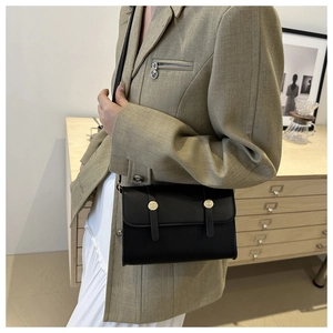 Classic black rectangular crossbody bag with gold hardware shown on a model side view