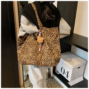 Detail of leopard print canvas tote bag with shoulder strap and plush bear charm