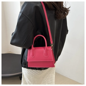 Rose pink leather crossbody bag shown on a model wearing a black jacket and white skirt