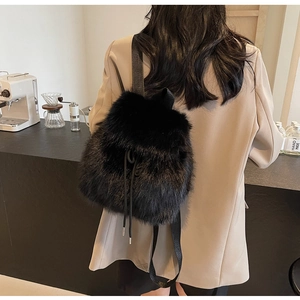Back view of a person wearing a fuzzy black faux fur drawstring backpack for winter fashion