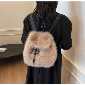 Detail of soft faux fur texture and black drawstring closure on camel plush backpack