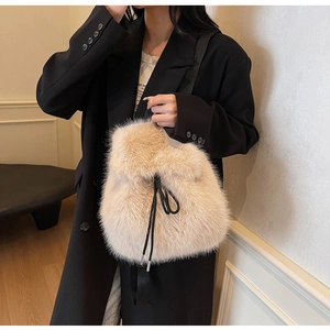 Close-up of cream plush bucket bag with drawstring closure and canvas strap on a model