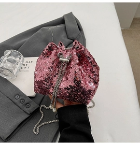 Secchiello di paillettes rosa con catena argentata su sfondo blazer grigio elegante