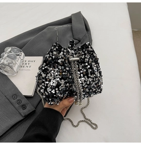 Dettaglio di paillettes su borsa a secchiello nera con coulisse di perle e catena