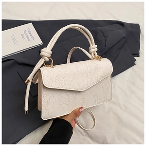 Close-up of beige PU leather crossbody bag with floral lace embossing and knotted handle