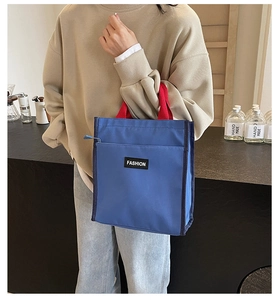 Détail du sac à lunch en tissu oxford bleu avec anses rouges et poche zippée