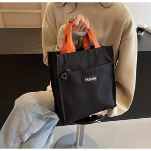 Detail of black nylon tote bag with orange handles and fashion zipper pocket for commuting