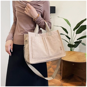 Dettaglio della borsa tote in velluto beige con etichetta laterale e trama a coste morbide