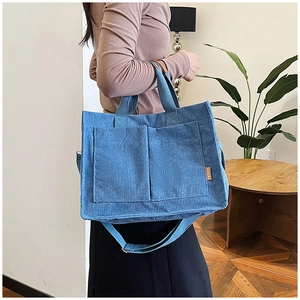Detailed view of blue corduroy tote bag with dual front pockets and fashion patch