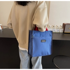 Blue nylon lunch tote bag with red handles and fashion label for daily office use