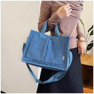 Dettaglio della borsa tote in velluto a coste blu con tasche frontali e tracolla regolabile