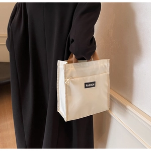 Détail du sac fourre-tout en toile crème avec poignées tissées brunes et texte